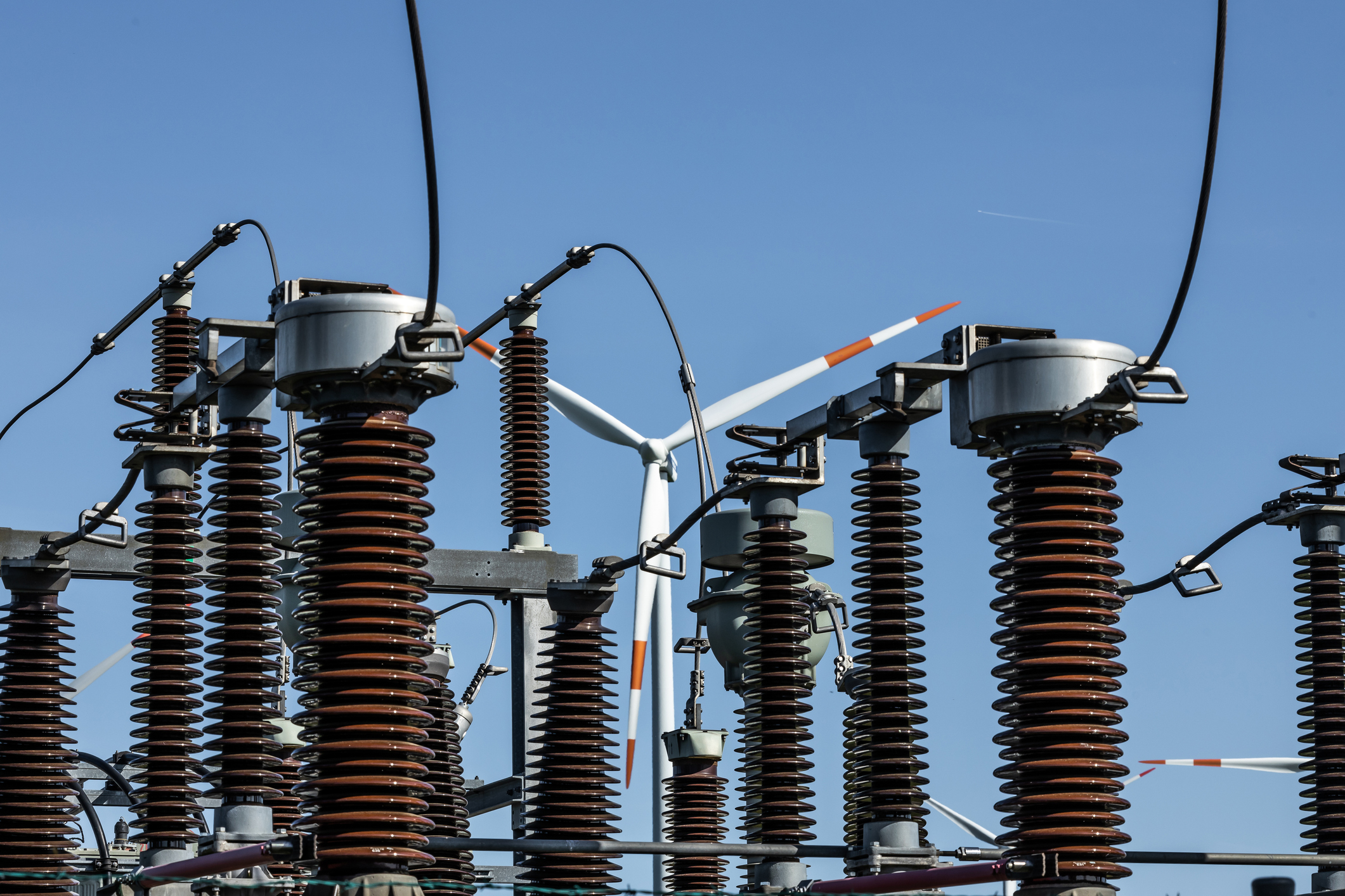 High-voltage electrical substation with a wind turbine in the background